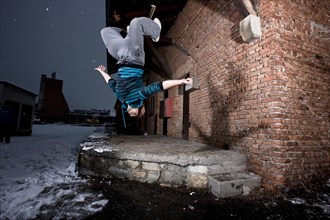 Freerunner doing a somersault at an old industrial site