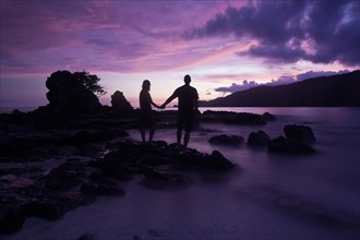 Couple standing on the beach after sunset