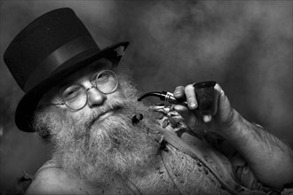 Elderly man with a long beard wearing a top hat and glasses