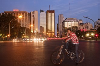 Young man sitting on his bike waiting at the crossroads of Av del Libertador - Crucero Gral Belgrano