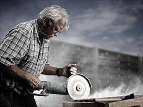 Stonemason cutting a stone slab with an angle grinder with a cutting disc