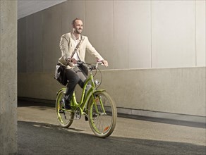 Man carrying a bag over his shoulder while riding a bicycle in the city
