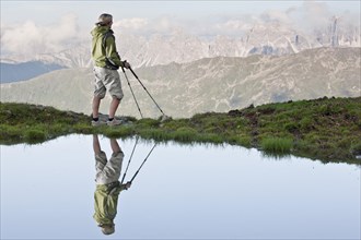 Reflection of a female hiker small lake looking at the Kalkkoegel range
