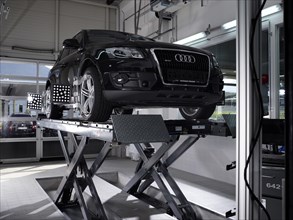 Car on a hoist with fitted pressure test panels for the wheel alignment