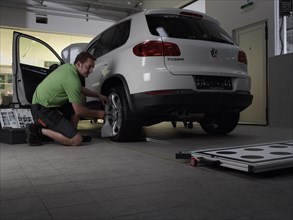 Car mechanic taking axis measurements with a laser