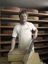 Dairyman cutting a mountain cheese