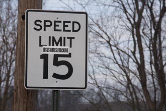 A sticker on a road sign near a natural gas well in the process of hydraulic fracturing or fracking in rural Lycoming County