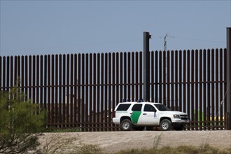 A Border Patrol vehicle at the border fence that separates the United States from Mexico