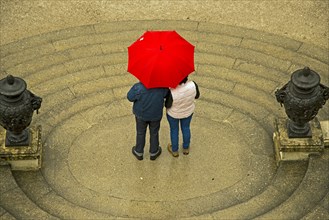 Couple standing under a red umbrella
