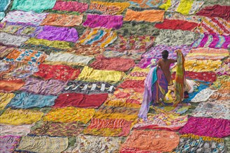 Colourful saris are laid out on the sand for drying after washing