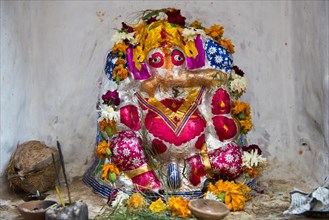 Hindu temple shrine with a colourfully painted Ganesha statue and offerings