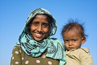 Indian woman with headscarf holding a little boy in her arms