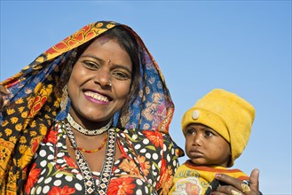 Smiling Indian women with a colourful scarf holding a small child in her arms