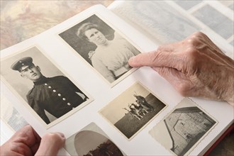 Hand of an old man pointing to a historical photograph in a photo album