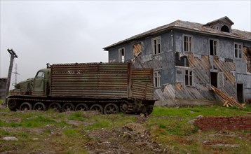 AT-T caterpillar all-terrain vehicle in front of a derelict house in a rural locality