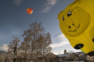 Red hot air balloon travelling against a blue sky