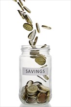 Savings jar with coins pouring into it