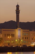 Floodlit buildings at the Corniche of Muttrah dominated by the minaret of the Rasool Azam Mosque