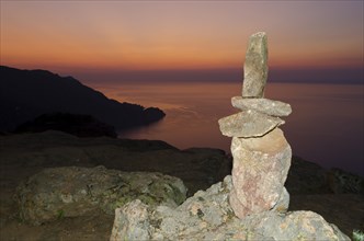 A typical cairn in the Calanche of Piana in front of a colorful sunset sky illuminated by a flash unit. The Calanche of Piana is in the western part of the island Corsica