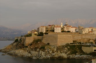 The citadel (castle) of Calvi surrounded by the mediterranean sea in front of the steep mountains of Corsica. Calvi is in the department Haute-Corse