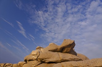 Bizarre granite rocks at the coast of the mediterranean sea in Calvi below a blue sky with some clouds. Calvi is in the department Haute-Corse