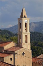 The church of the small village Evisa illuminated by warm evening light surrounded by mountains. Evisa is in the department Corse-du-Sud