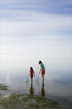 Woman and girl with dip nets standing in the Wadden Sea