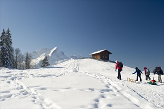 Sledgers and a wooden house on a snow-covered hill