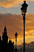 The Conciergerie and the typical Parisian street lights against dramatic clouds in the evening