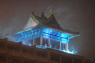 Rooftop pagoda on a modern building during a snowstorm