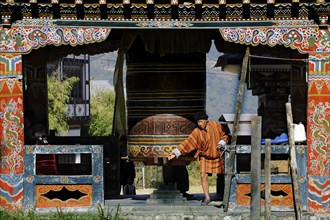 Man turning the large prayer wheel in the town centre of Mongar