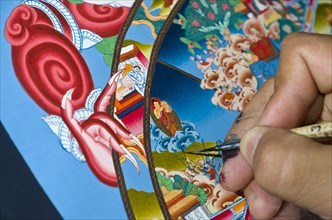 Artist painting a colourful Thangka in an art school