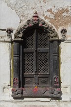 Ornate carved wooden window of a small shrine in the hills above Pashupatinath Temple