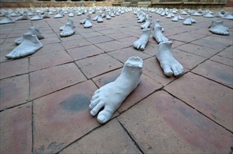White sculptures of feet arranged as an art installation