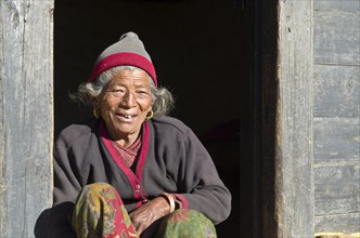 Old woman sitting in the doorway of a farmers house