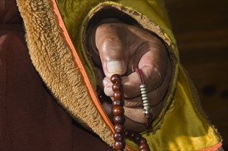 Hand of a monk praying and counting beads at a mala