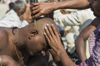 Pilgrim having his head shaved during Kumbha Mela
