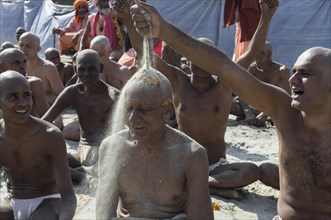 Man putting sand on the head of a another man joining the initiation of new sadhus