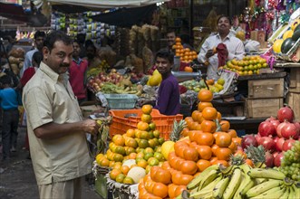 Street vendor arranging oranges for sale at a fruit stall