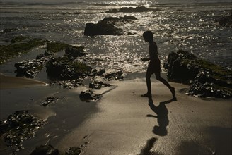 Young boy walking on the beach in the evening sun