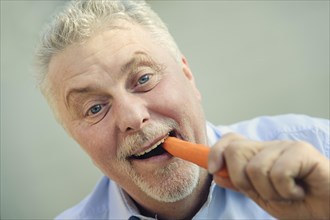 Senior eating a carrot with pleasure