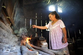Elderly woman in a basic kitchen cooking on an open fire