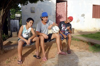 Young people with a football sitting in front of their home in a favela