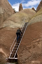 Visitor using a ladder on a hike through the tufa