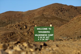 Welcome sign visible between rocks with GPS location information at the entrance of the Tatasberg Wilderness Camp
