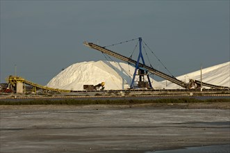 Heap of sea salt at the salt works Salins du Midi with an evaporation basin at front