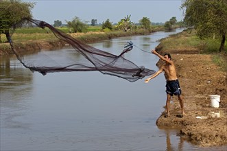 Fisherman fishing by casting a throw net in a river