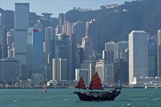 Traditional Chinese junk sailing before the skyscrapers of Hong Kong Central District