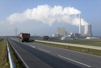 Lorry on a two-lane highway travelling in front of steam rising from a cooling tower and a chimney of Petershagen-Lahde coal-fired power station
