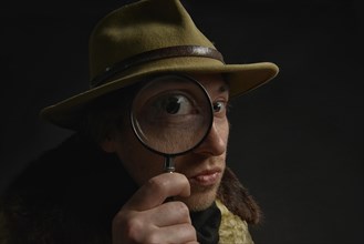 Man holding magnifying glass in front of his eye